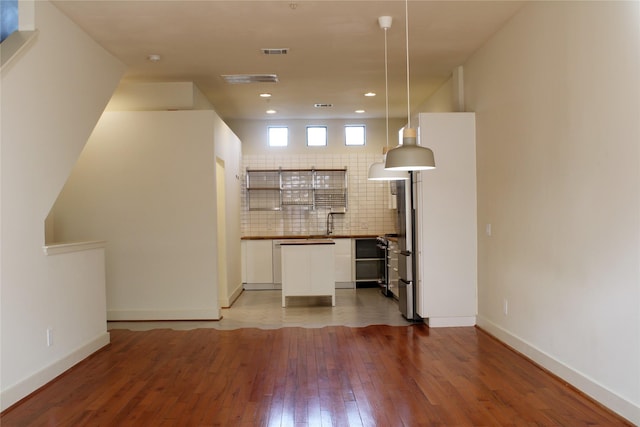 kitchen with sink, hardwood / wood-style flooring, white cabinets, pendant lighting, and backsplash