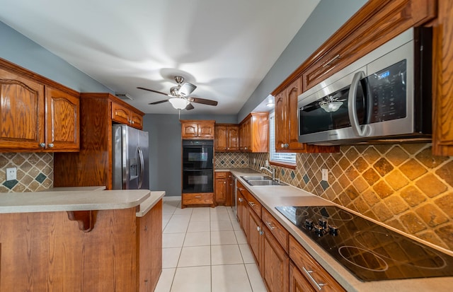 kitchen featuring a breakfast bar, backsplash, black appliances, sink, and light tile patterned floors