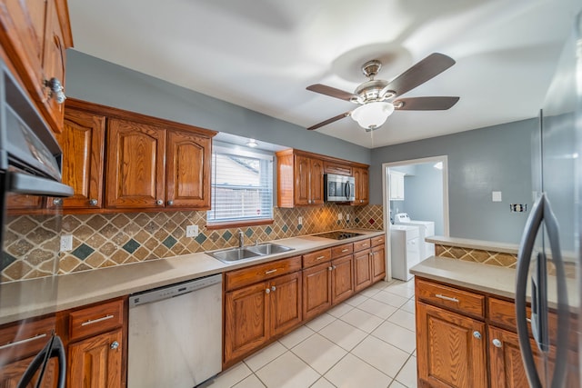 kitchen featuring appliances with stainless steel finishes, tasteful backsplash, sink, washing machine and clothes dryer, and light tile patterned flooring