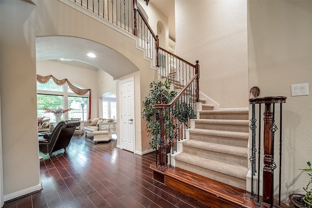 stairs featuring wood-type flooring and a high ceiling