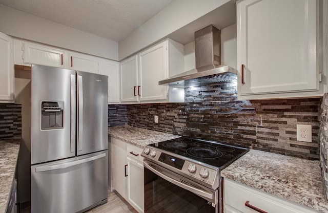 kitchen with light stone counters, white cabinetry, appliances with stainless steel finishes, wall chimney range hood, and backsplash