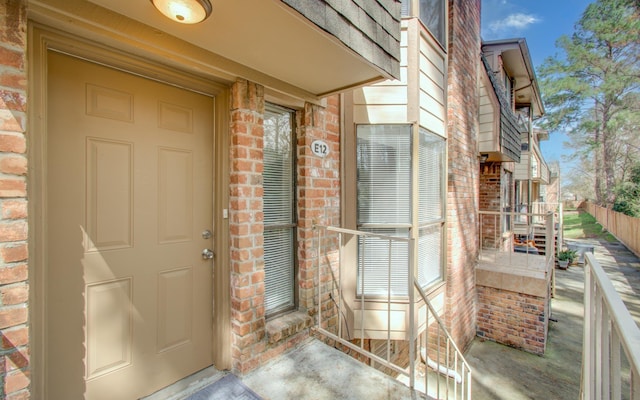 property entrance with fence and brick siding