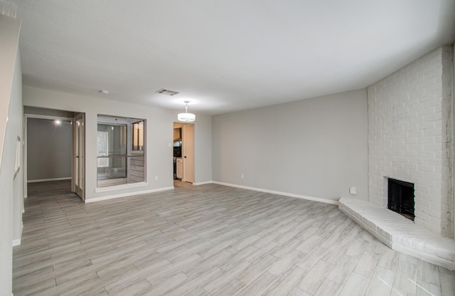 unfurnished living room featuring light wood-style floors, visible vents, a fireplace, and baseboards