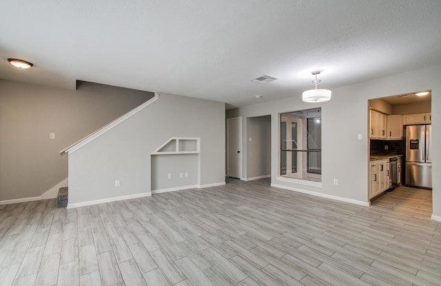 unfurnished living room featuring baseboards, visible vents, light wood finished floors, and stairs