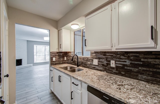 kitchen featuring backsplash, a sink, white cabinetry, and light stone countertops