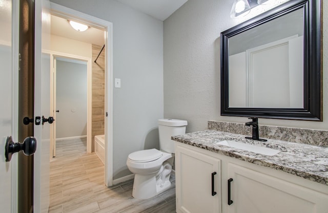 full bathroom featuring baseboards, bathing tub / shower combination, toilet, wood tiled floor, and vanity