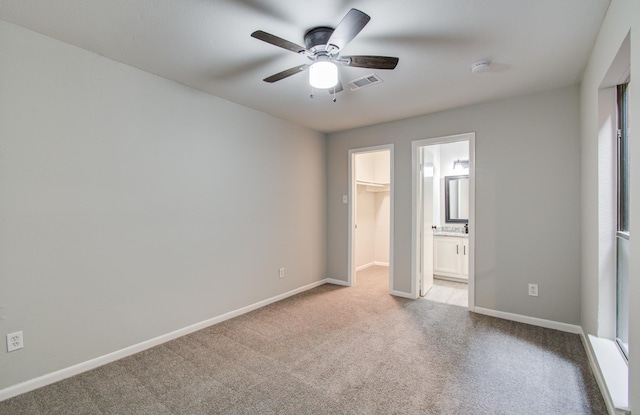 unfurnished bedroom with a walk in closet, visible vents, ensuite bathroom, carpet flooring, and baseboards