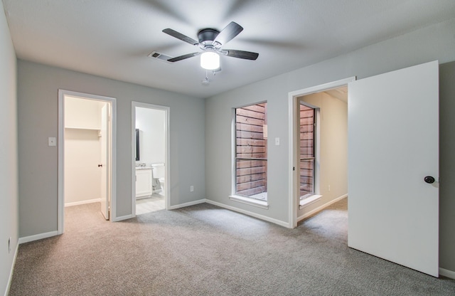 unfurnished bedroom featuring carpet floors, ensuite bath, a spacious closet, and visible vents