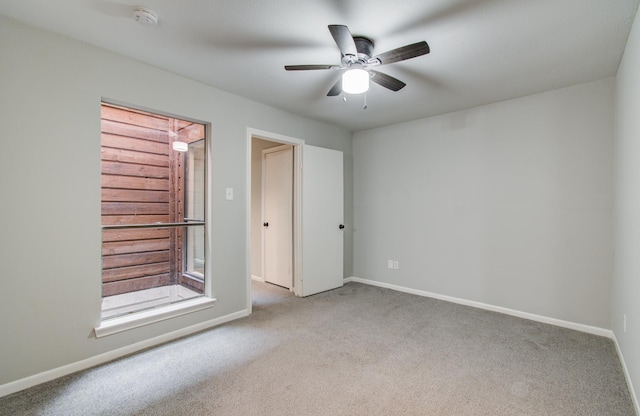 carpeted empty room featuring baseboards and a ceiling fan