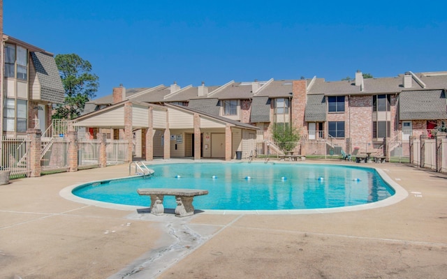 community pool with a residential view, fence, and a patio