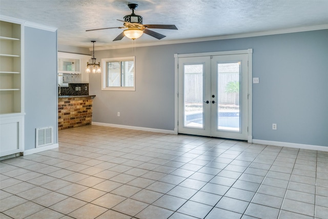 unfurnished room featuring french doors, built in features, a textured ceiling, light tile patterned flooring, and ceiling fan with notable chandelier