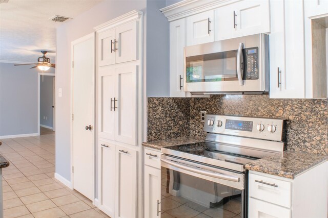 kitchen with white cabinetry, stainless steel appliances, tasteful backsplash, dark stone countertops, and light tile patterned floors