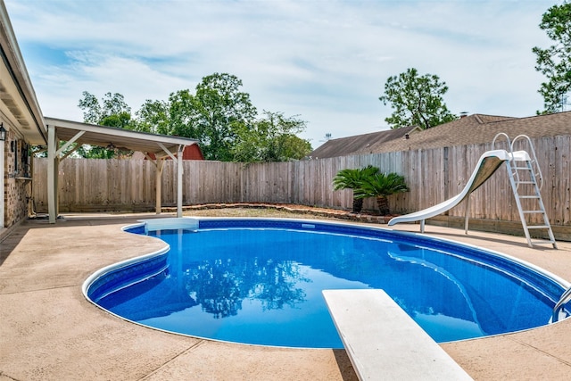 view of pool with a diving board and a water slide