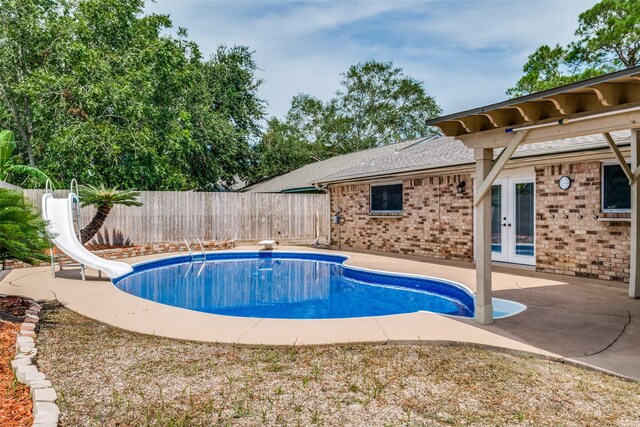 view of swimming pool with a diving board, french doors, a water slide, and a patio