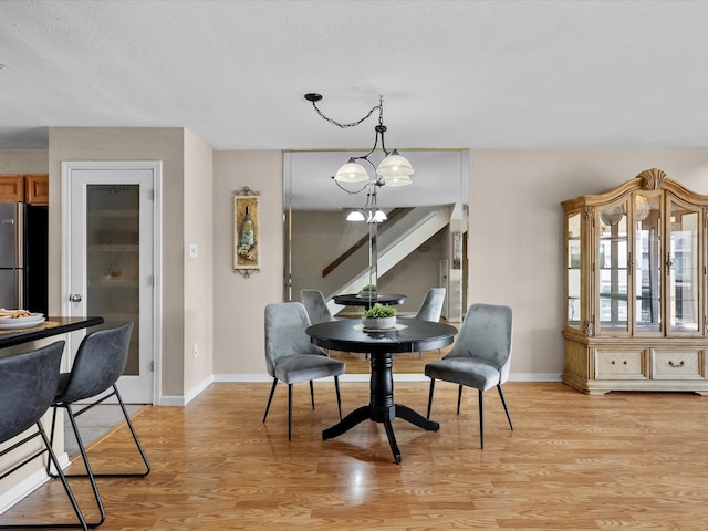 dining area with a chandelier, a textured ceiling, and light hardwood / wood-style flooring