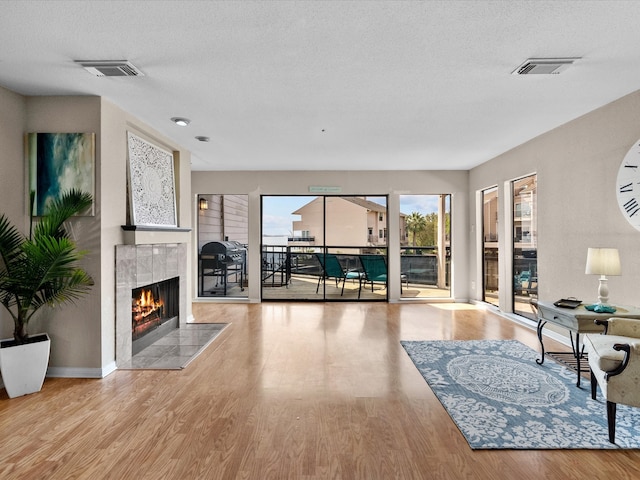 living room featuring a fireplace, a textured ceiling, and light hardwood / wood-style flooring