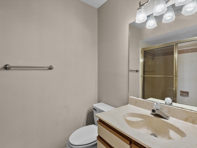 bathroom featuring a shower with shower door, vanity, and toilet