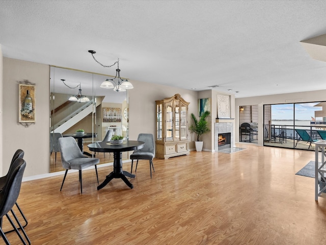 dining room with a fireplace, hardwood / wood-style flooring, a textured ceiling, and an inviting chandelier