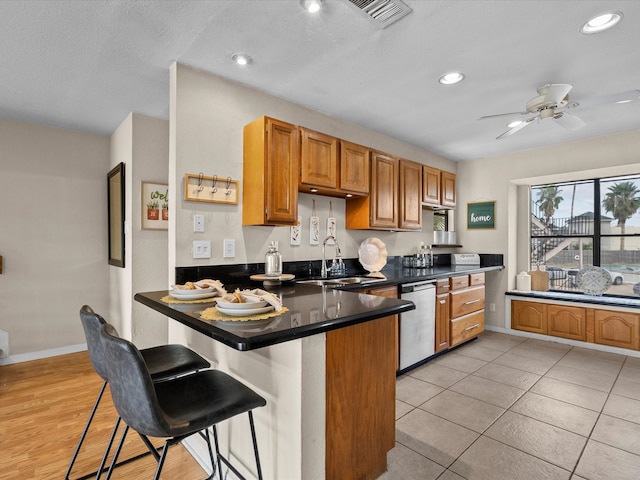 kitchen with light tile patterned flooring, sink, a breakfast bar, kitchen peninsula, and stainless steel dishwasher