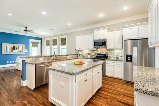 kitchen featuring light stone countertops, kitchen peninsula, white cabinets, and stainless steel appliances