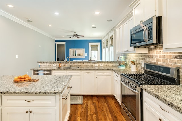 kitchen featuring appliances with stainless steel finishes, sink, light stone counters, and white cabinetry