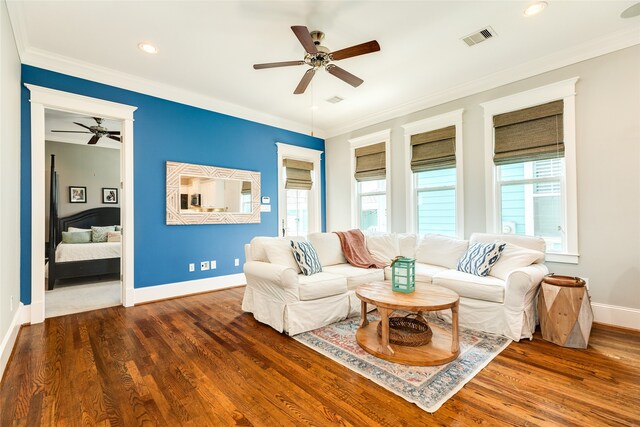 living room with ceiling fan, dark wood-type flooring, ornamental molding, and a healthy amount of sunlight