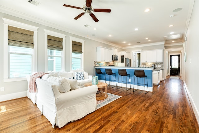 living room with hardwood / wood-style flooring, crown molding, ceiling fan, and a healthy amount of sunlight