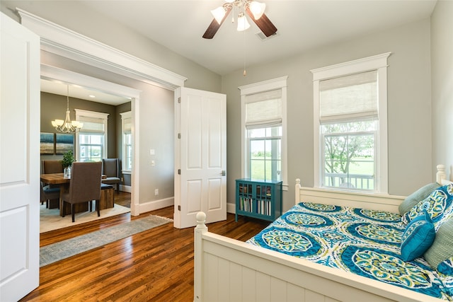 bedroom featuring dark wood-type flooring and ceiling fan with notable chandelier