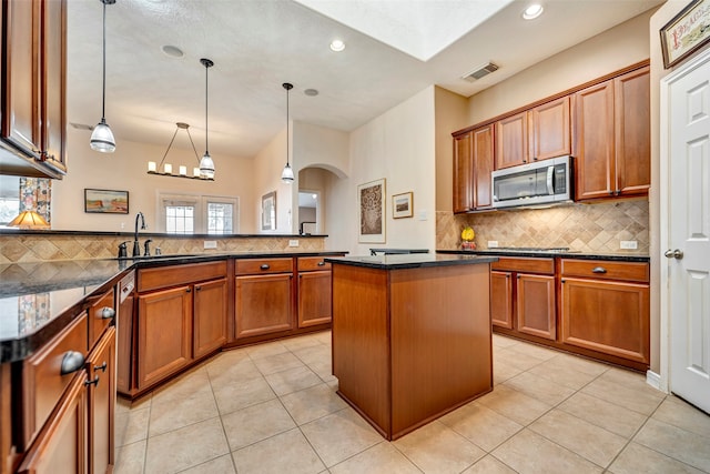 kitchen with sink, appliances with stainless steel finishes, light tile patterned floors, a center island, and pendant lighting