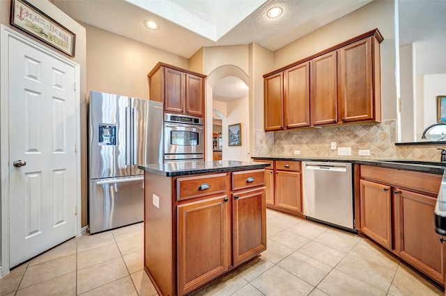 kitchen with stainless steel appliances, sink, a textured ceiling, light tile patterned floors, and a kitchen island