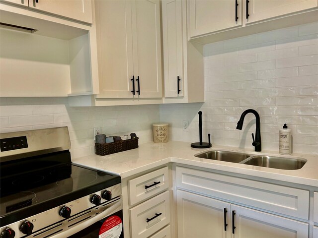 kitchen featuring stainless steel range, backsplash, white cabinetry, and sink