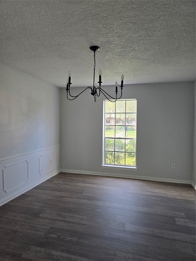 unfurnished dining area with a textured ceiling, dark hardwood / wood-style floors, and an inviting chandelier