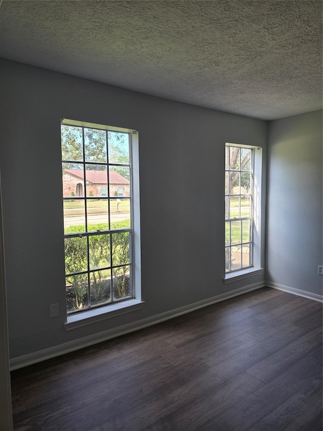 spare room featuring a textured ceiling, dark wood-type flooring, and a wealth of natural light