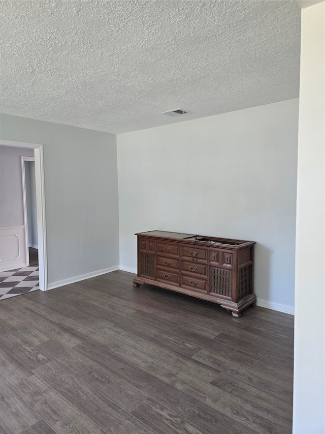 spare room with dark wood-type flooring and a textured ceiling