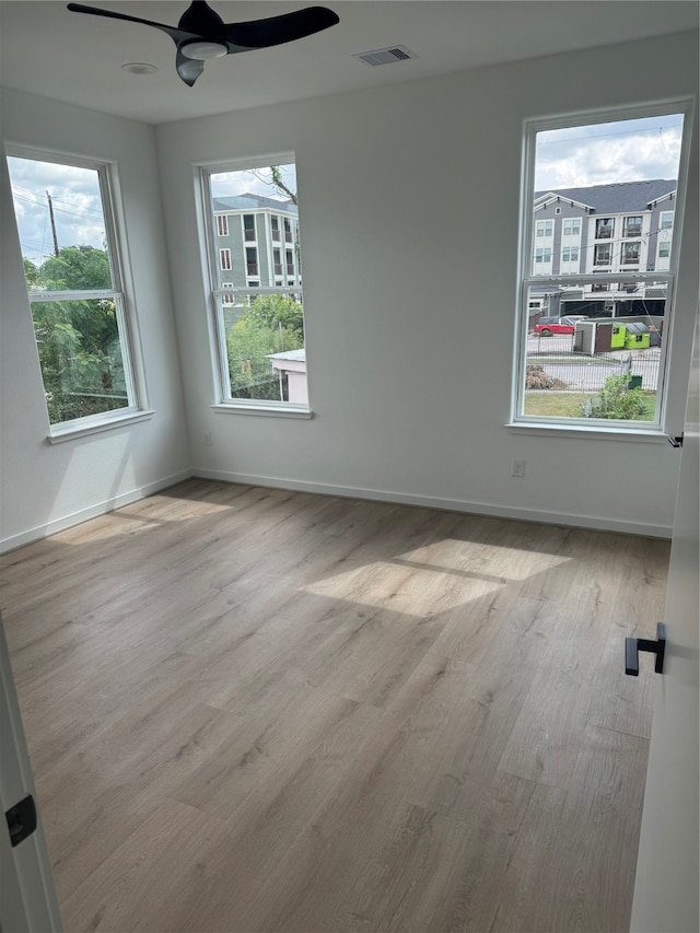 spare room with light wood-type flooring, a wealth of natural light, and ceiling fan