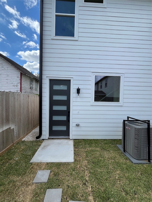 property entrance with a yard and central AC unit