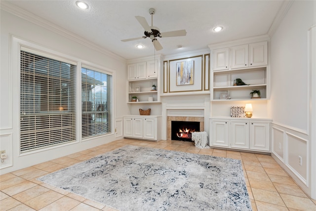 living room featuring ceiling fan, a tile fireplace, and ornamental molding