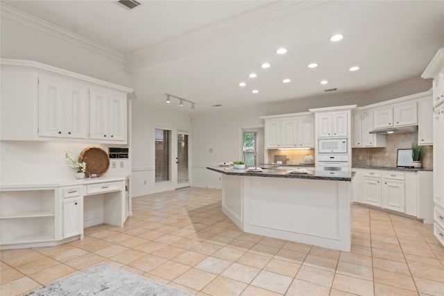 kitchen featuring ornamental molding, dark stone countertops, light tile patterned floors, white appliances, and white cabinets