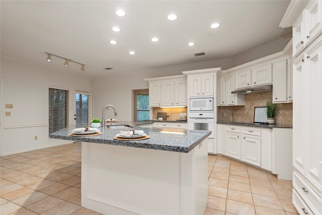 kitchen featuring sink, a kitchen island with sink, crown molding, white cabinetry, and white appliances