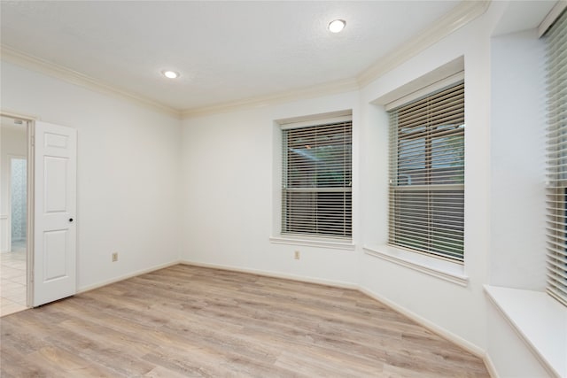 spare room featuring ornamental molding, light hardwood / wood-style floors, and a textured ceiling