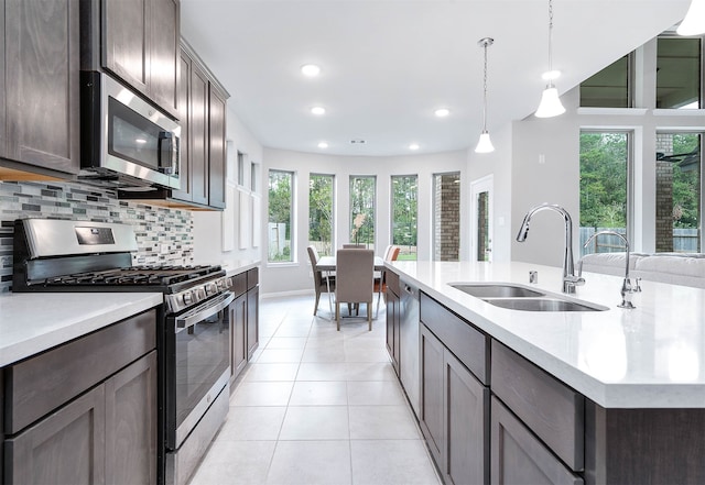 kitchen featuring a wealth of natural light, stainless steel appliances, a center island with sink, and sink