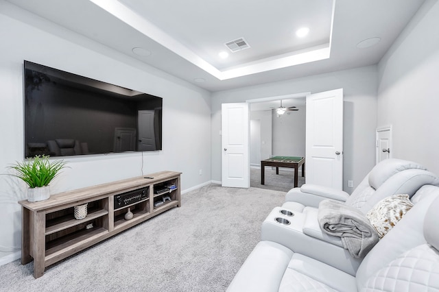 living room featuring carpet floors, ceiling fan, and a raised ceiling