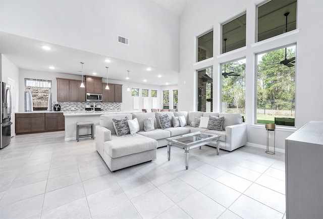 living room with a wealth of natural light, light tile patterned floors, and a high ceiling