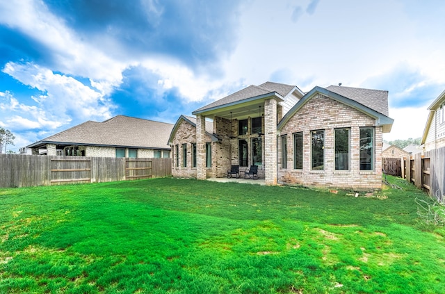 rear view of property featuring a patio and a yard