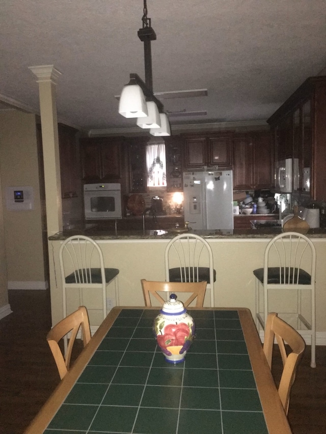 dining space with decorative columns, a textured ceiling, and tile patterned floors