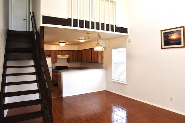 12264 Bob White Dr Unit 122, Houston, TX 77035 - kitchen with pendant lighting, under cabinet range hood, baseboards, a peninsula, and brown cabinets