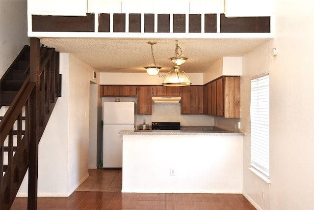 kitchen featuring white refrigerator, a textured ceiling, black range, dark tile patterned flooring, and hanging light fixtures