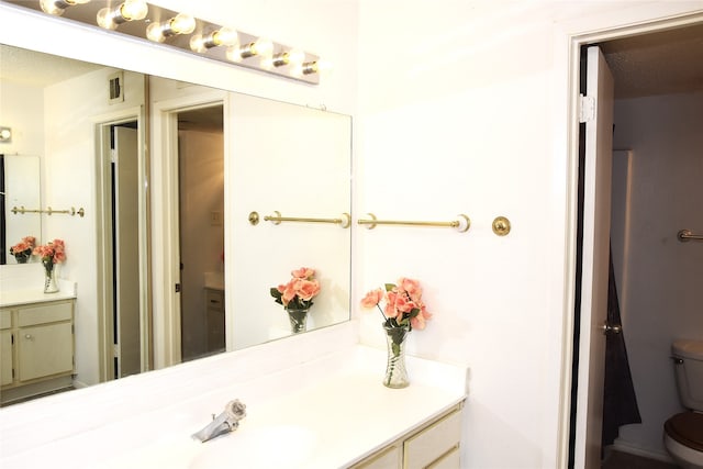 bathroom featuring vanity, a textured ceiling, and toilet