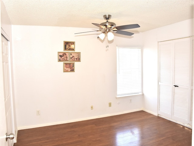 unfurnished bedroom featuring a textured ceiling, dark wood-type flooring, and ceiling fan