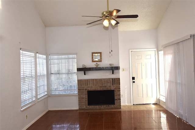 unfurnished living room featuring ceiling fan, a textured ceiling, a brick fireplace, and plenty of natural light